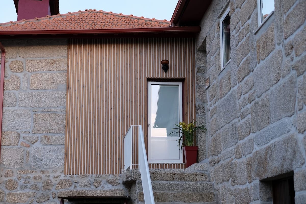 A stone building with a wooden slatted wall and a door.
