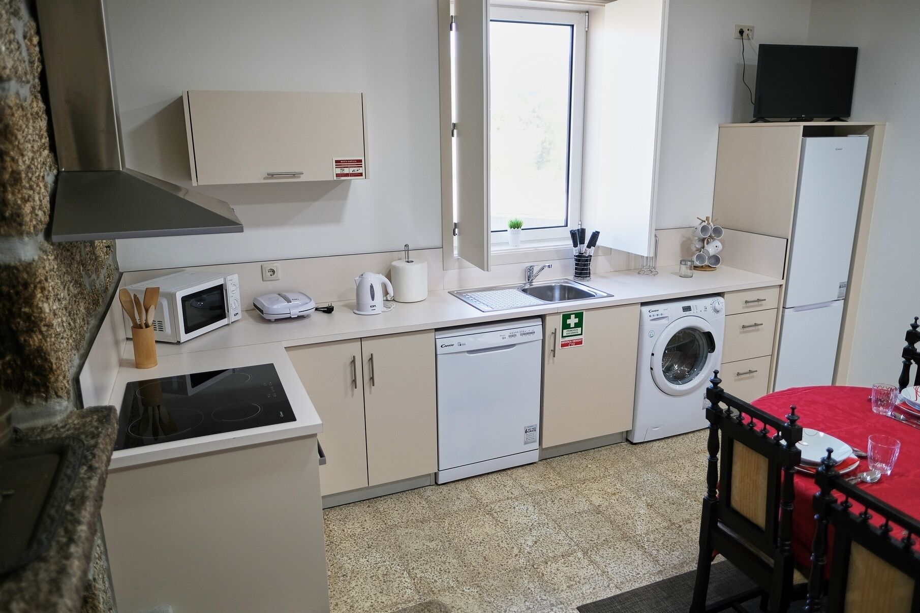A compact kitchenette with a microwave, kettle, toaster, and a washing machine.