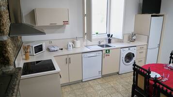 A compact kitchenette with a microwave, kettle, toaster, and a washing machine.