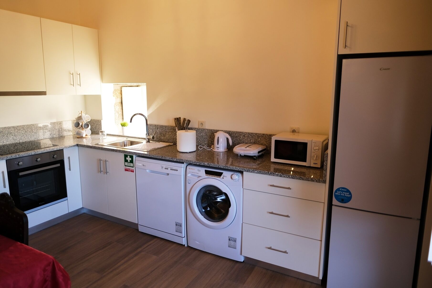 A compact kitchen with a washing machine, microwave, and a refrigerator.