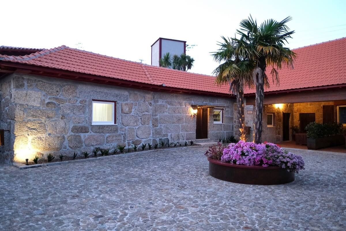 A stone building with a red-tiled roof, a small window, and a well-lit entrance.