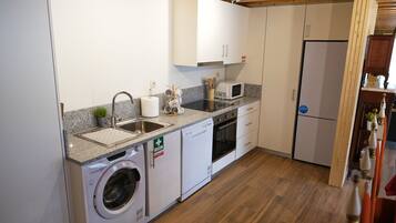 A compact kitchen with a washing machine, a microwave, and a refrigerator.