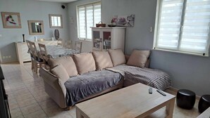 Un salon moderne comprenant un canapé d’angle, une table basse et un coin repas avec des chaises et une table.