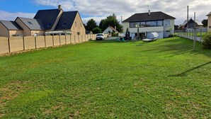 Un quartier résidentiel avec des maisons, une pelouse verdoyante et une voiture blanche garée dans l’allée.
