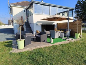A modern two-story house with a patio area featuring outdoor furniture and a large umbrella. - Maison mer (Saint-Germain-sur-Ay)