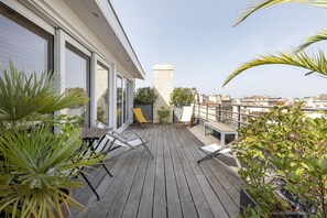 A wooden deck with outdoor furniture, potted plants, and a cityscape view. - Artist Duplex & Terrace - 170m² (Burdeos)