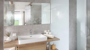 Un baño moderno con un lavabo grande, espejo y ducha.