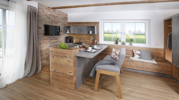 Una cocina moderna con pared de ladrillo, suelo de madera y un ventanal con vistas al campo.