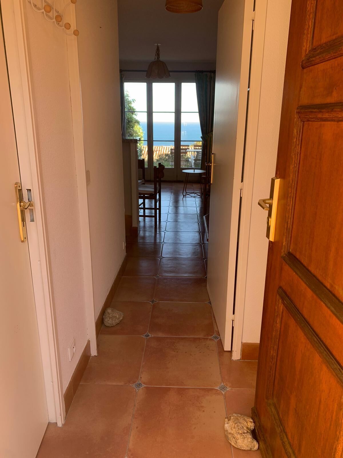 A hallway with a view to a balcony, tiled flooring, and a wooden door.