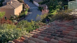 Una zona residencial en una ladera, con casas escalonadas, un camino sinuoso y cielo despejado.