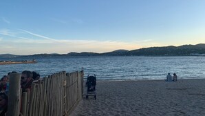 Una playa con una cerca de madera, un cochecito de bebé y gente relajándose.