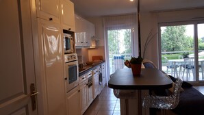 Una cucina moderna con mobili bianchi, un tavolo da pranzo e vista sull'esterno tramite ampie finestre.