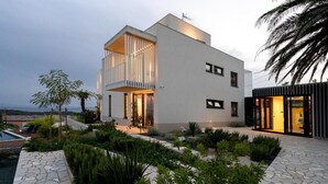 A modern two-story house with a balcony, stone pathway, and tropical plants. - Beach front home in Palit with sauna (Palit)
