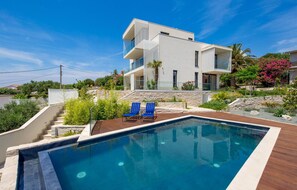 A modern two-story house with a swimming pool, blue lounge chairs, and a landscaped garden. - Beach front home in Palit with sauna (Palit)
