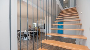 Ein modernes Interieur mit Treppe, Holzböden und einem Essbereich mit Stühlen und Tisch.