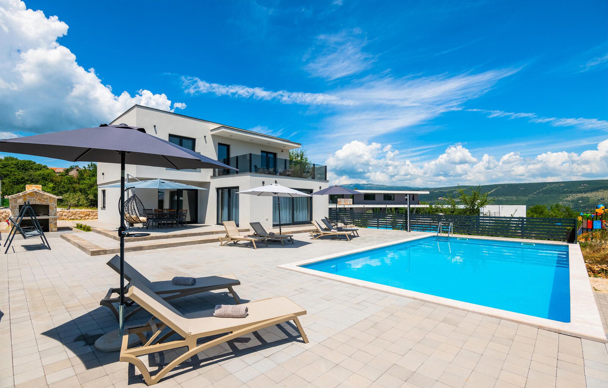Uma villa moderna com piscina, área de estar ao ar livre e lareira de pedra.