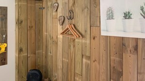 A wooden wall with a hanging coat rack, a small fan, and a framed picture of cacti.