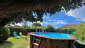 A wooden above-ground swimming pool with a ladder, surrounded by a grassy lawn and a tree. - House/Gite/Cottage rated 1 star, with above-ground pool, garden. (Puget-sur-Argens)