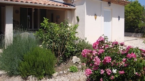 A small house with a tiled roof, an air conditioning unit, and a garden with pink flowers. - House/Gite/Cottage rated 1 star, with above-ground pool, garden. (Puget-sur-Argens)