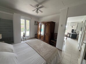 A bedroom with a bed, a wardrobe, a desk with a television, and a ceiling fan.