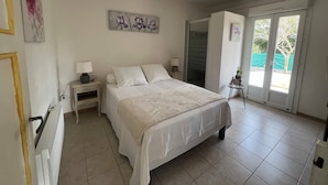 A bedroom with a bed, nightstands, a ceiling fan, and a sliding glass door leading to a balcony. - House/Gite/Cottage rated 1 star, with above-ground pool, garden. (Puget-sur-Argens)