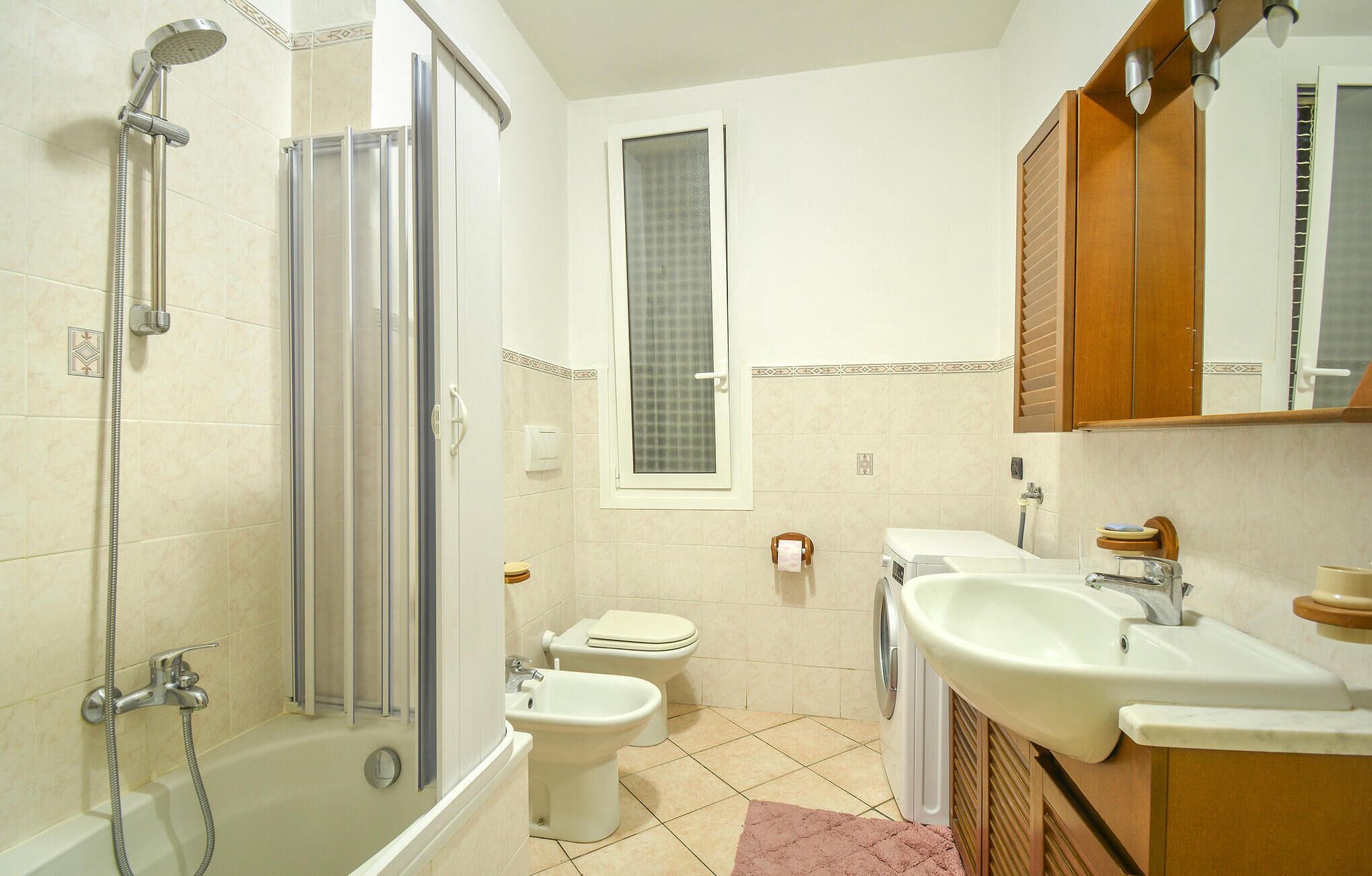 A bathroom with a shower, toilet, sink, and mirror.