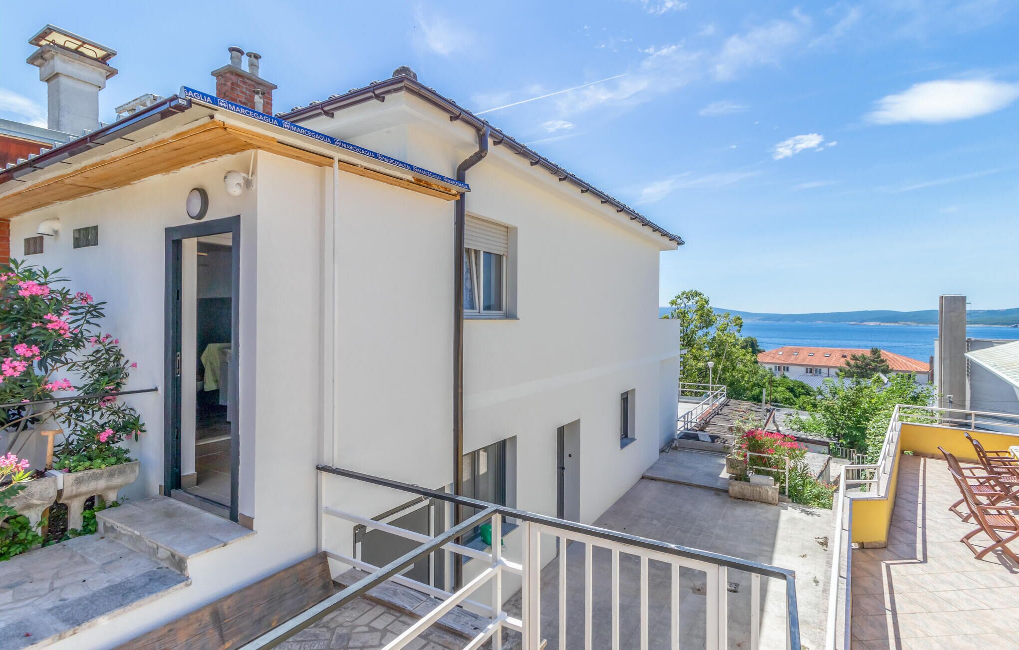 A white building with a balcony and a view of the sea.