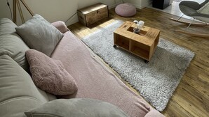 Un salon moderne comprenant un canapé, une table basse, un téléviseur et une fenêtre donnant sur un paysage verdoyant.