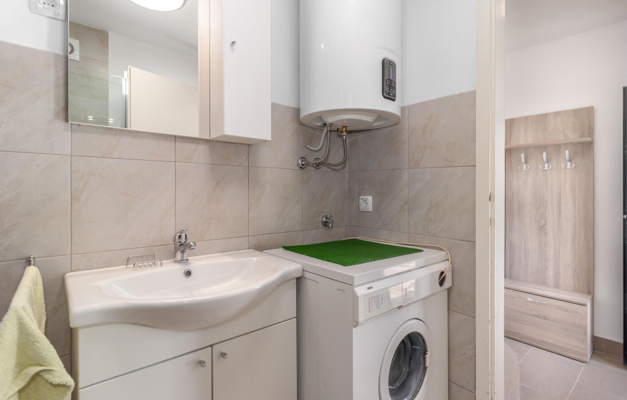 Casa de banho moderna com lavatório, espelho e máquina de lavar roupa.