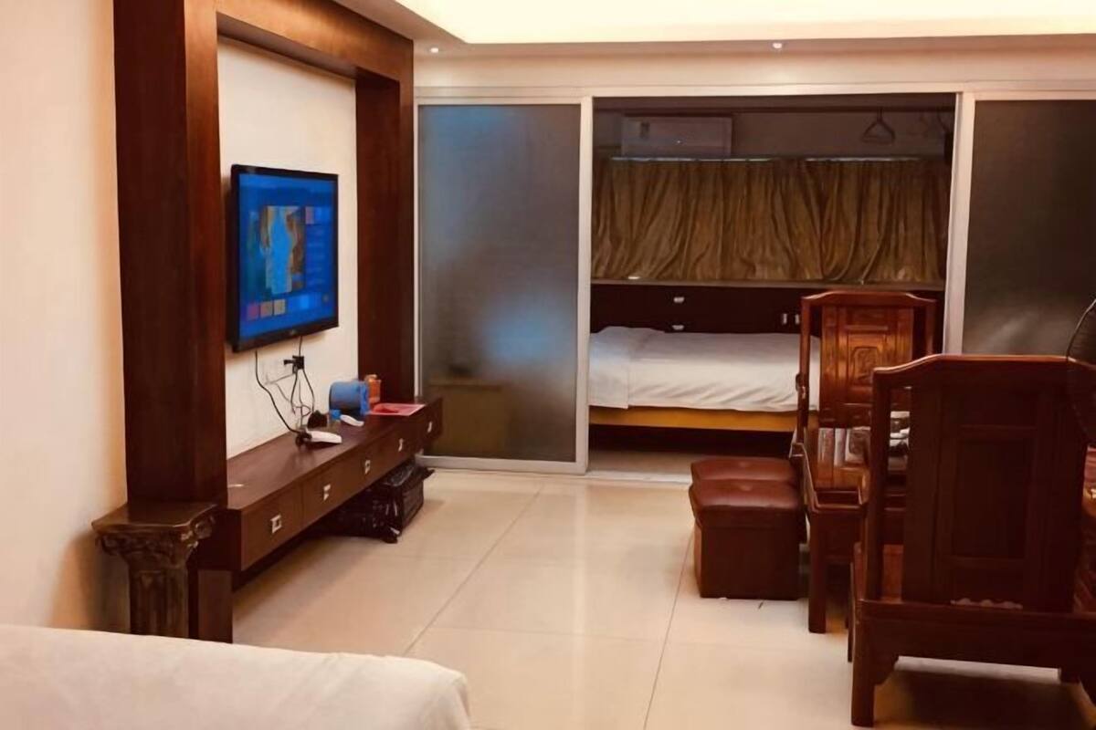 A hotel room with a bed, a TV, a desk, a chair, a wardrobe, and a sliding door closet.