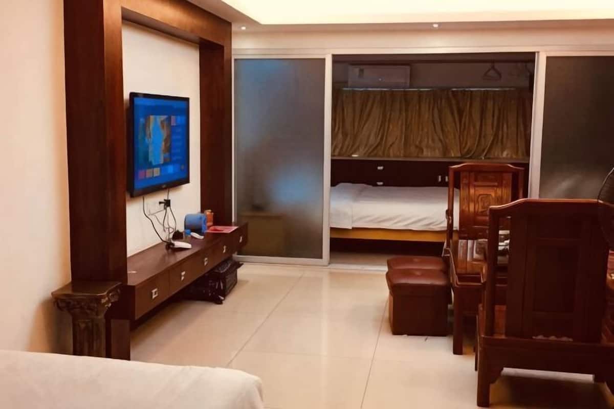 Habitación de hotel con cama, televisor, escritorio, silla, armario y closet con puerta corredera.