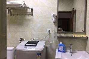 A bathroom with a hairdryer, a towel rack, a mirror, a sink, and a bottle of dish soap. - Wenxin Hotel (Sihui)