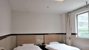 A hotel room with two beds, a window with curtains, and a ceiling light. - Wenxin Hotel (Sihui)