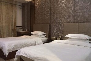 A hotel room with two beds, a nightstand, a mirror, and a patterned wall. - Wenxin Hotel (Sihui)