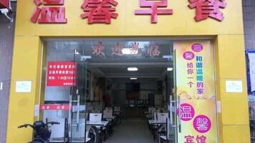 A restaurant with a yellow facade and red signage. Inside, there are tables and chairs arranged for dining.
