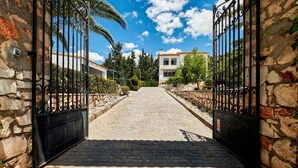 Ein gepflasterter Weg führt zu einem verschlossenen Eingang mit Steinmauern und Metalltoren.