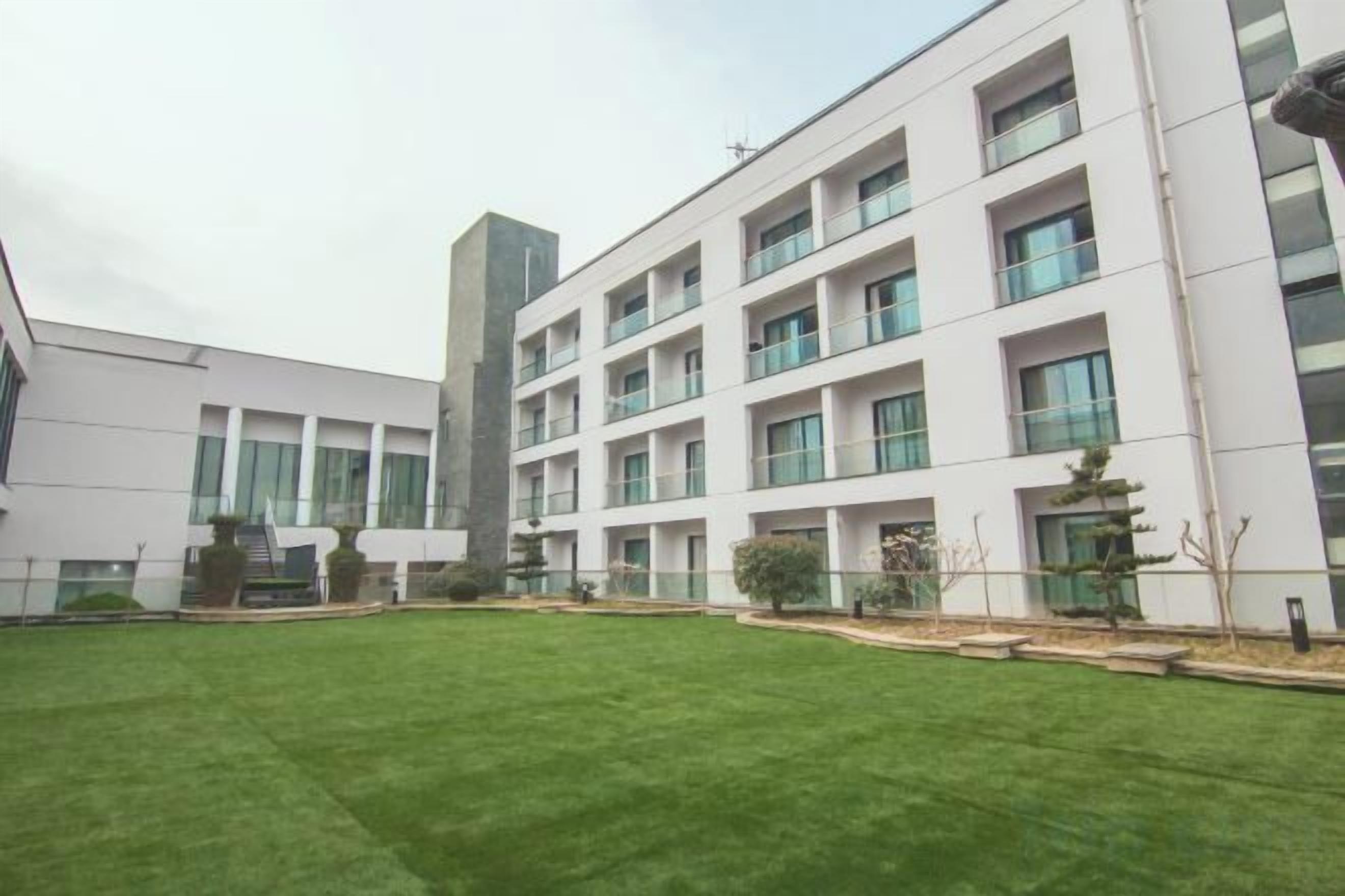 Un edificio moderno con varios pisos, amplias ventanas y un césped cuidado.