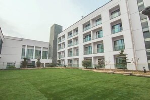 Un edificio moderno con varios pisos, amplias ventanas y un césped cuidado.
