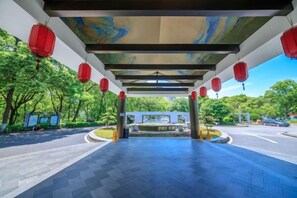 An outdoor covered walkway with red lanterns, a tiled floor, and a view of a road and greenery. - Baoqing Villa (Shaoyang)