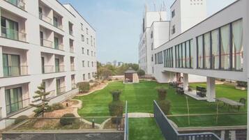 A modern building with multiple floors, a central courtyard with grass, and a small gazebo.