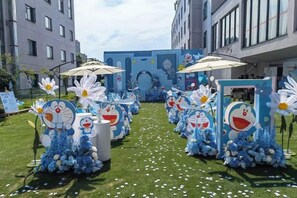 A courtyard with a blue and white themed setup featuring cartoon characters, umbrellas, and flowers. - Baoqing Villa (Shaoyang)