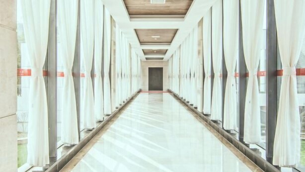 A long, narrow corridor with large windows on both sides, leading to a door at the end. - Baoqing Villa (Shaoyang)