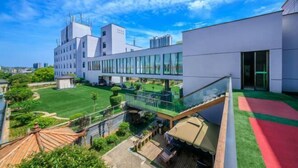 A modern building with a glass facade, a rooftop terrace, and a well-maintained lawn. - Baoqing Villa (Shaoyang)