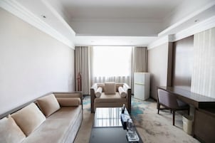 Una habitación de hotel moderna con sofá, mesa de centro, escritorio y vistas al exterior.