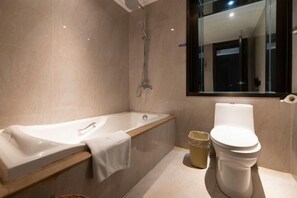 Un baño moderno con bañera, inodoro y un espejo grande.