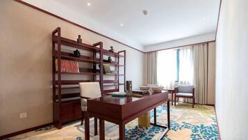 Habitació d'hotel amb una biblioteca de fusta, una taula de menjador amb cadires i un gran finestral amb cortines.