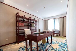 A hotel room with a wooden bookshelf, a dining table with chairs, and a large window with curtains. - Baoqing Villa (Shaoyang)