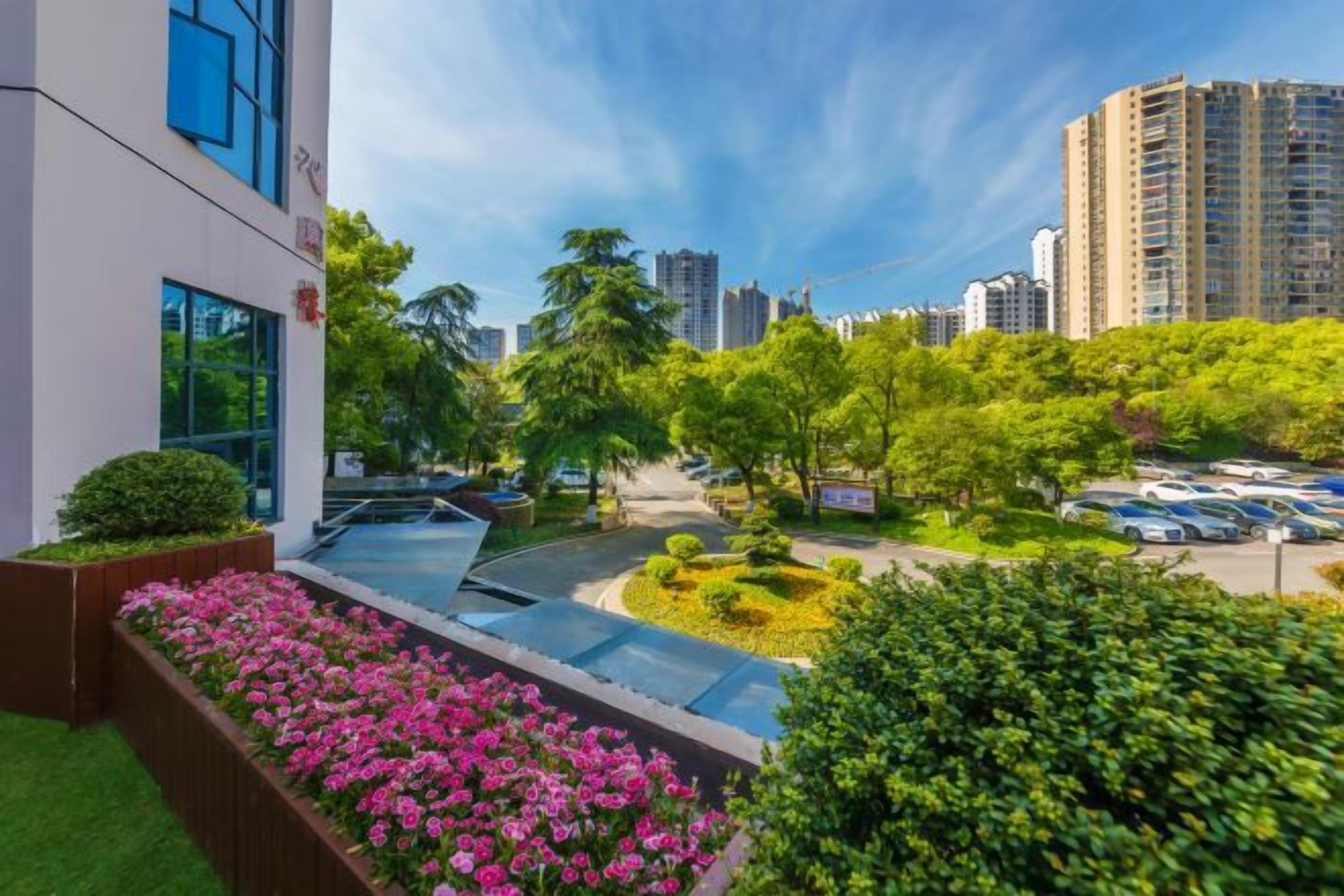 A modern building with a rooftop garden, surrounded by greenery and high-rise buildings.