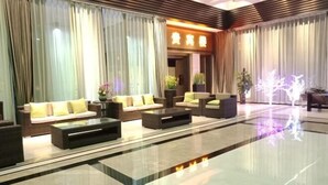 A modern hotel lobby with a seating area, a reception desk, and a decorative plant arrangement. - Baoqing Villa (Shaoyang)