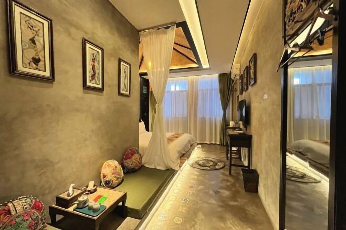 Ein modernes Hotelzimmer mit Bett, einer kleinen Sitzecke, einem Schminktisch und Kunstwerken an den Wänden.
